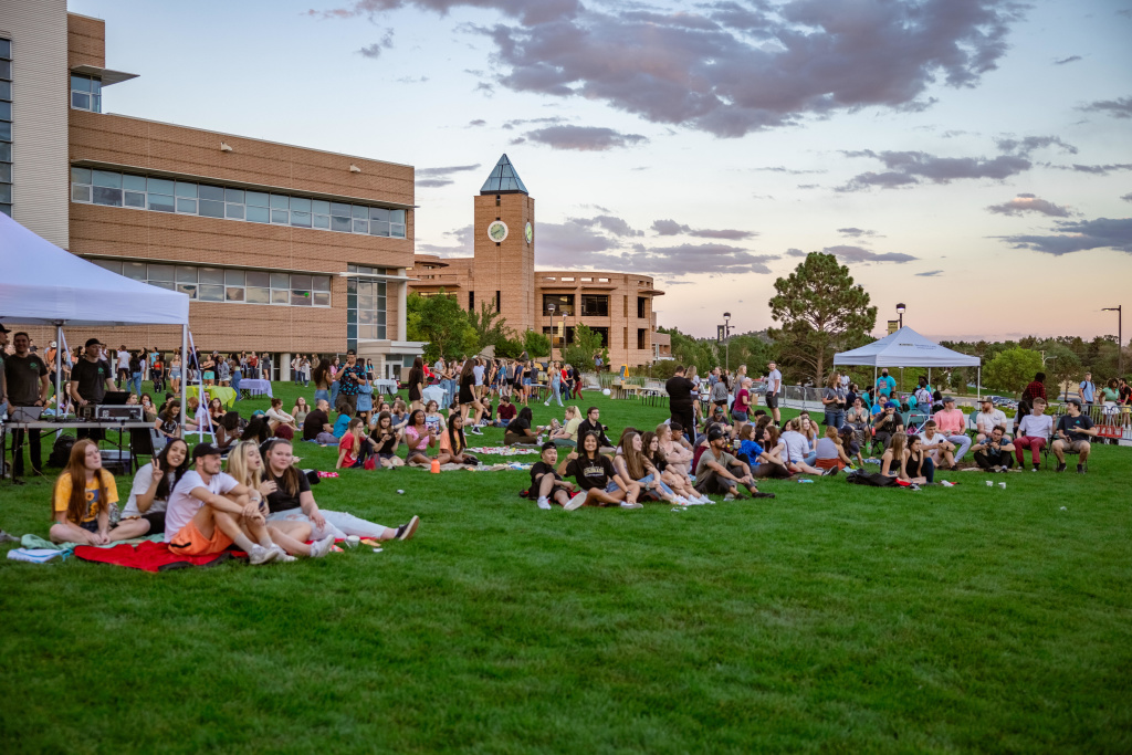 Students sitting on the UCCS west lawn for welcome week event