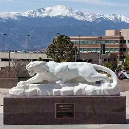 Mountain lion statue in front of snowy Pikes Peak